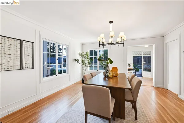 a dining room with wooden floor a chandelier a glass table and chairs