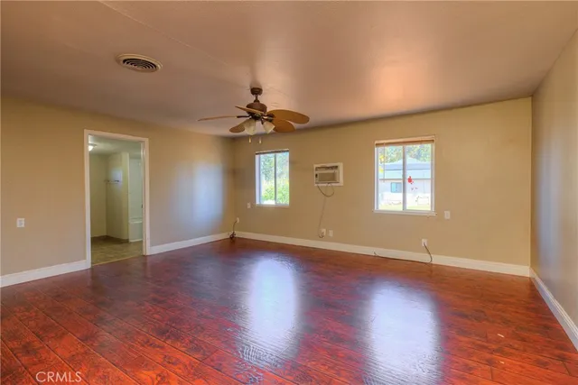 a view of an empty room with a window and wooden floor