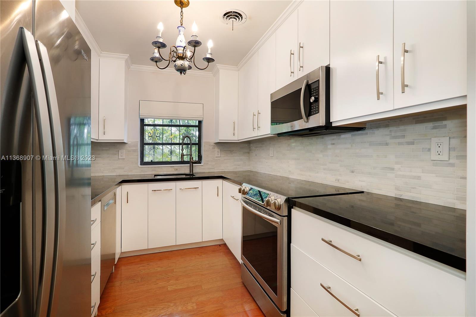 6970 Sunset Drive Miami, FL 33143 - Photo 7 of 30 a kitchen with stainless steel appliances granite countertop a refrigerator sink and microwave