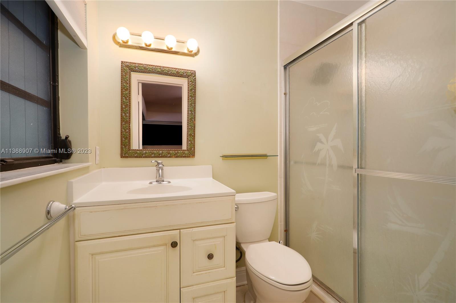 6970 Sunset Drive Miami, FL 33143 - Photo 9 of 30 a bathroom with a toilet a sink a mirror a vanity and shower
