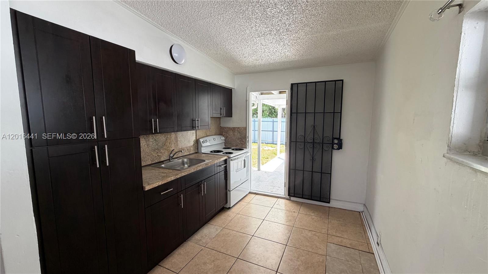 2230 Service Road Opa-Locka, FL 33054 - Photo 17 of 25 a kitchen with granite countertop a refrigerator and a stove top oven