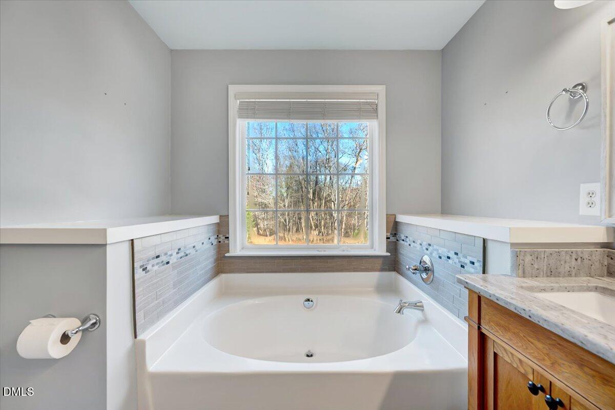 1716 Middle Ridge Drive Willow Spring, NC 27592 - Photo 20 of 41 a bathroom with a granite countertop sink a window and a bathtub