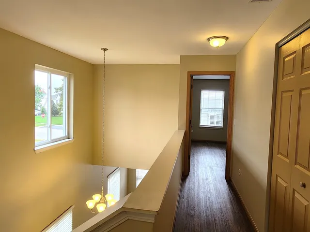 a view of a hallway with wooden floor and a living room