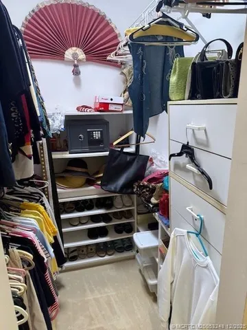 a view of walk in closet with clothes and shoes
