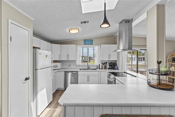 a kitchen with granite countertop stainless steel appliances a refrigerator a sink a stove and white cabinets