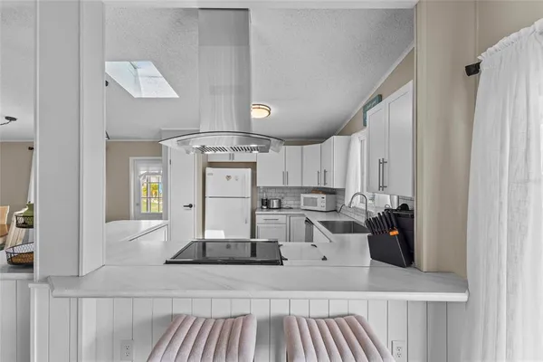a kitchen with stainless steel appliances a sink a stove and white cabinets next to a window