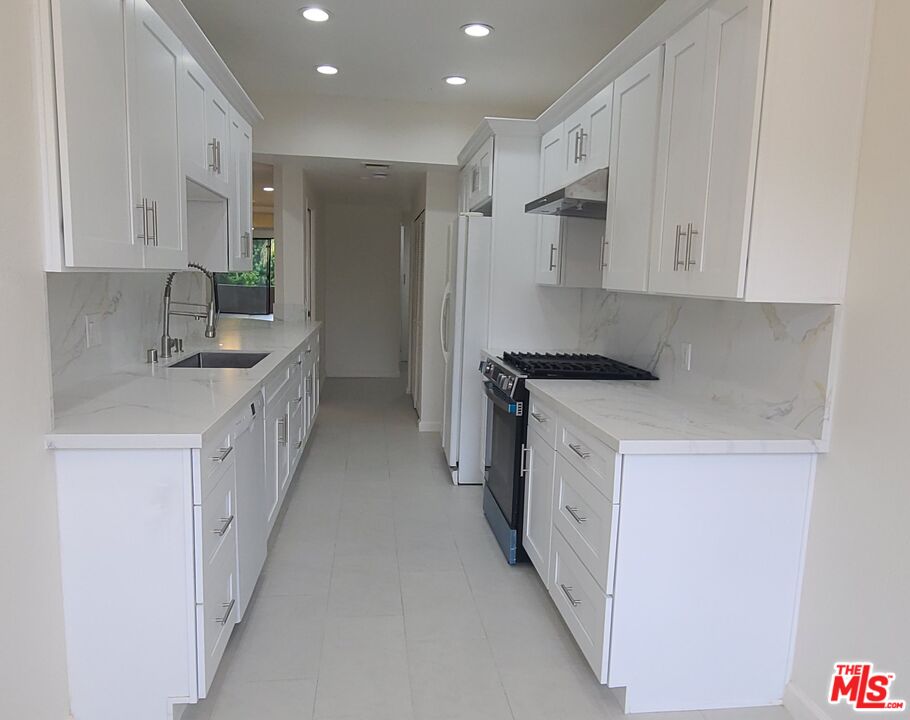 1557 South Beverly Glen Boulevard, Unit 104 Los Angeles, CA 90024 - Photo 17 of 44 a kitchen with white cabinets and white appliances