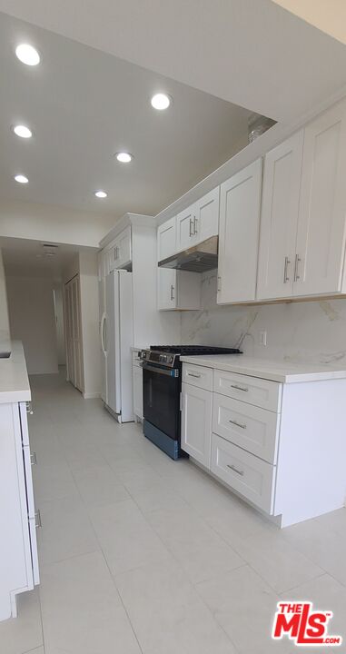 1557 South Beverly Glen Boulevard, Unit 104 Los Angeles, CA 90024 - Photo 20 of 44 a kitchen with stainless steel appliances granite countertop a refrigerator and a stove