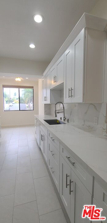 1557 South Beverly Glen Boulevard, Unit 104 Los Angeles, CA 90024 - Photo 23 of 44 a kitchen with granite countertop white cabinets and window