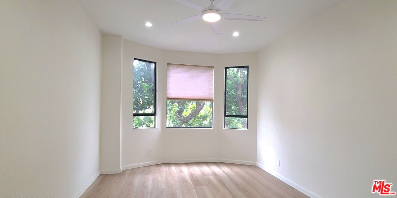 1557 South Beverly Glen Boulevard, Unit 104 Los Angeles, CA 90024 - Photo 29 of 44 an empty room with wooden floor and windows