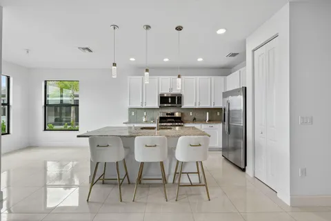 a kitchen with kitchen island granite countertop wooden cabinets and a refrigerator