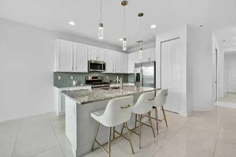 a kitchen with stainless steel appliances granite countertop a stove a sink a refrigerator and a microwave