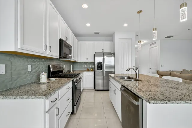 a kitchen with stainless steel appliances granite countertop a sink stove and refrigerator