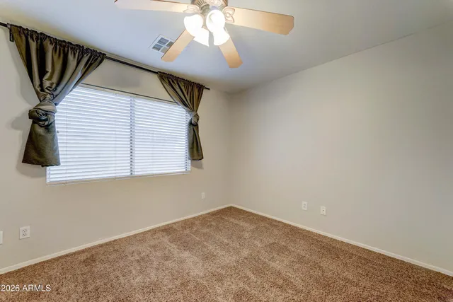 a view of an empty room and chandelier fan