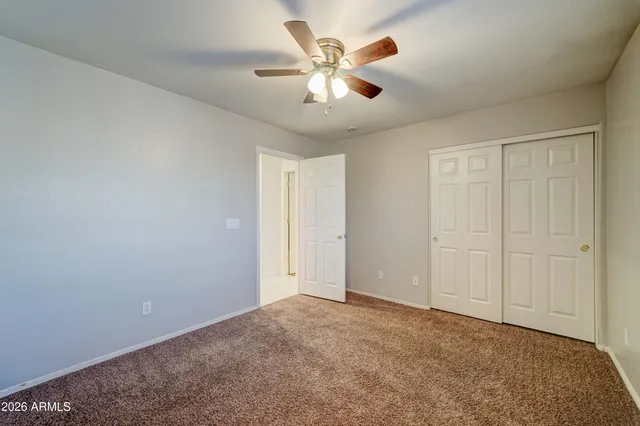 an empty room with chandelier fan and windows