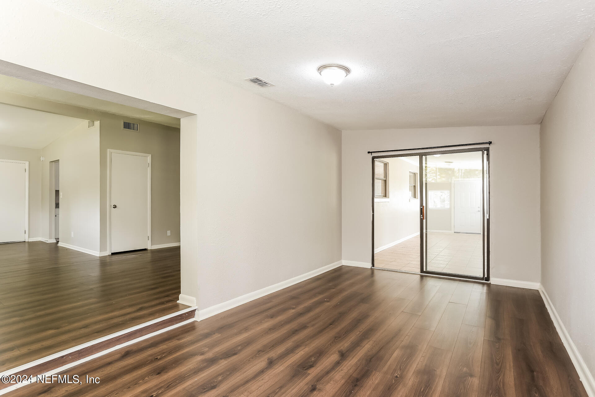 7003 Rollo Road Jacksonville, FL 32205 - Photo 10 of 21 a view of an empty room with wooden floor and a window