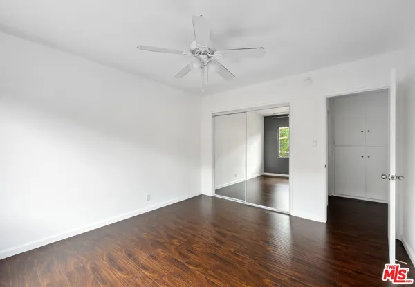 a view of empty room with wooden floor and fan