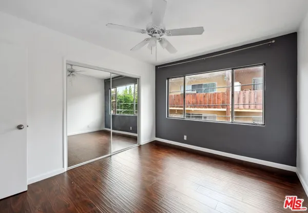 a view of an empty room with window and wooden floor