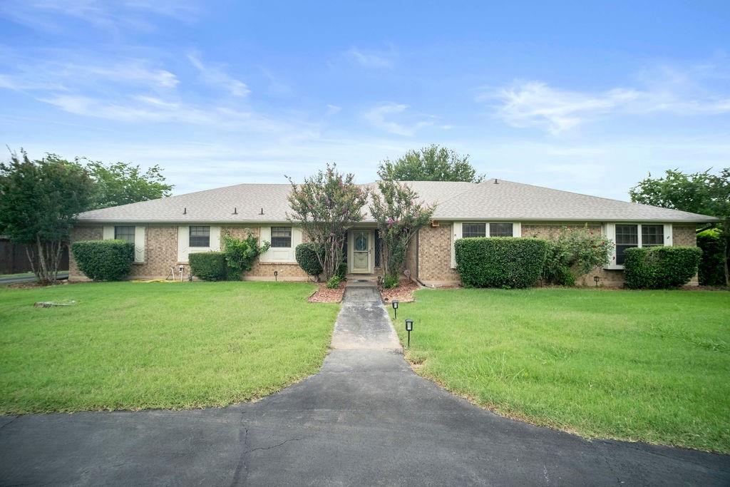 Single story home featuring a front lawn, brick siding, and asphalt driveway