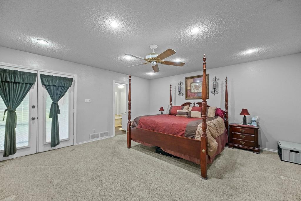6939 Calender Road Arlington, TX 76001 - Photo 19 of 40 Bedroom featuring a textured ceiling, carpet floors, access to exterior, baseboards, and ensuite bathroom