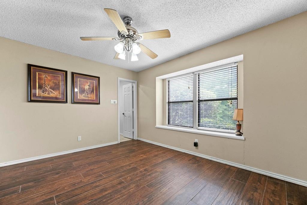 6939 Calender Road Arlington, TX 76001 - Photo 23 of 40 Unfurnished room featuring wood finished floors, baseboards, ceiling fan, and a textured ceiling
