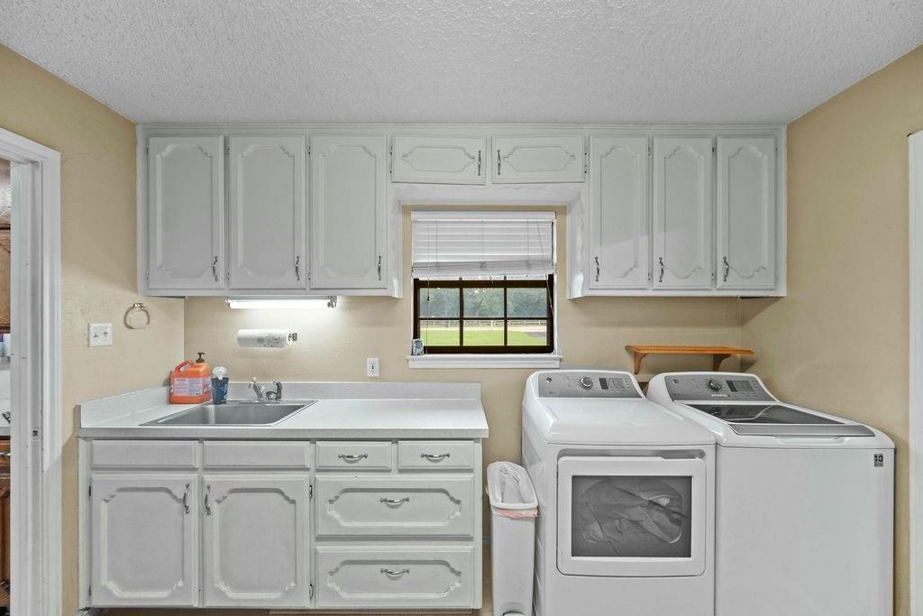 6939 Calender Road Arlington, TX 76001 - Photo 24 of 40 Washroom featuring washer and dryer, a textured ceiling, and cabinet space