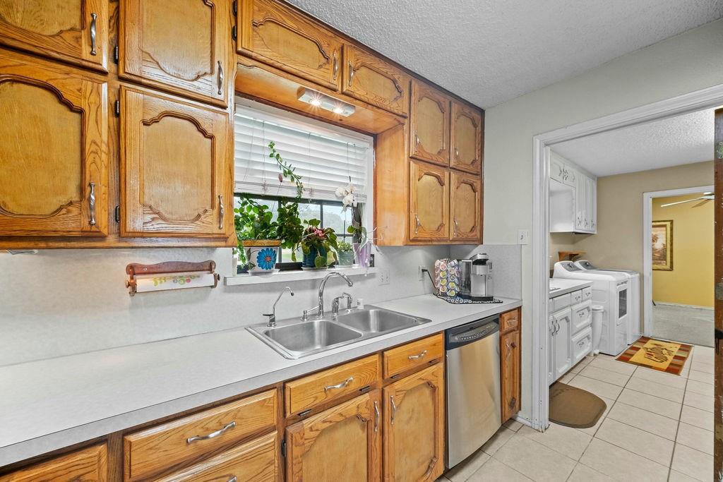 6939 Calender Road Arlington, TX 76001 - Photo 29 of 40 Kitchen featuring dishwasher, a sink, washing machine and clothes dryer, light countertops, and brown cabinets