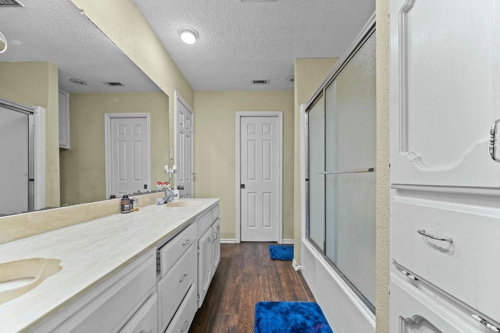 6939 Calender Road Arlington, TX 76001 - Photo 34 of 40 Full bath with double vanity, wood finished floors, a textured ceiling, and enclosed tub / shower combo