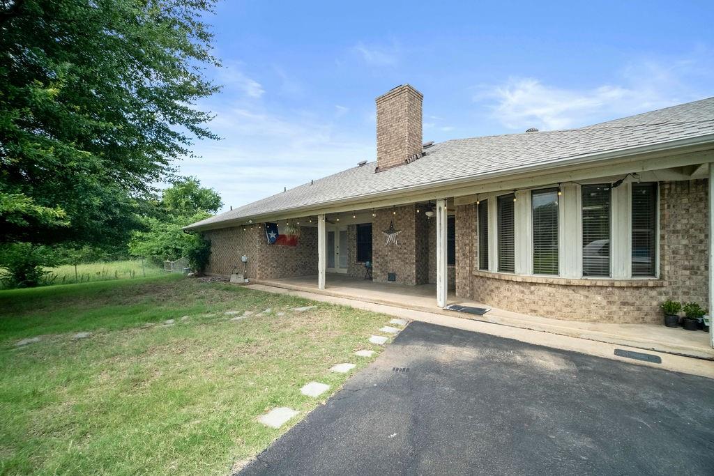 6939 Calender Road Arlington, TX 76001 - Photo 7 of 40 Rear view of house featuring a chimney, brick siding, a yard, and a patio area