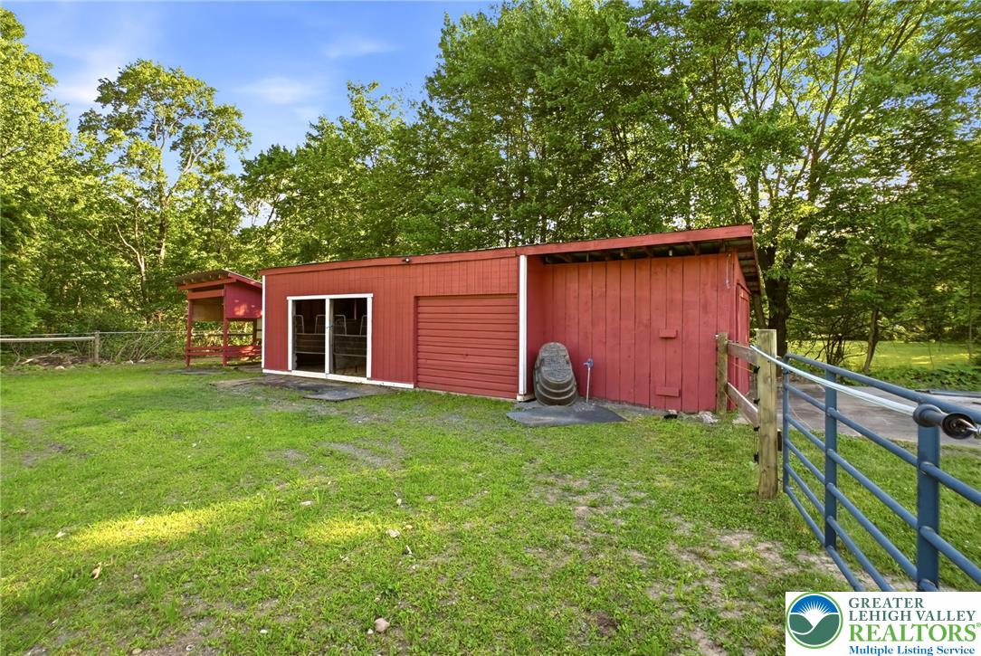 9033 Loop Road Slatington, PA 18080 - Photo 44 of 53 A vibrant red barn with a covered porch offers abundant storage and functional space amidst a verdant landscape.