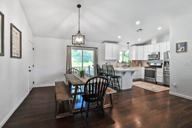 a open dining room with stainless steel appliances wooden floors a table and chairs