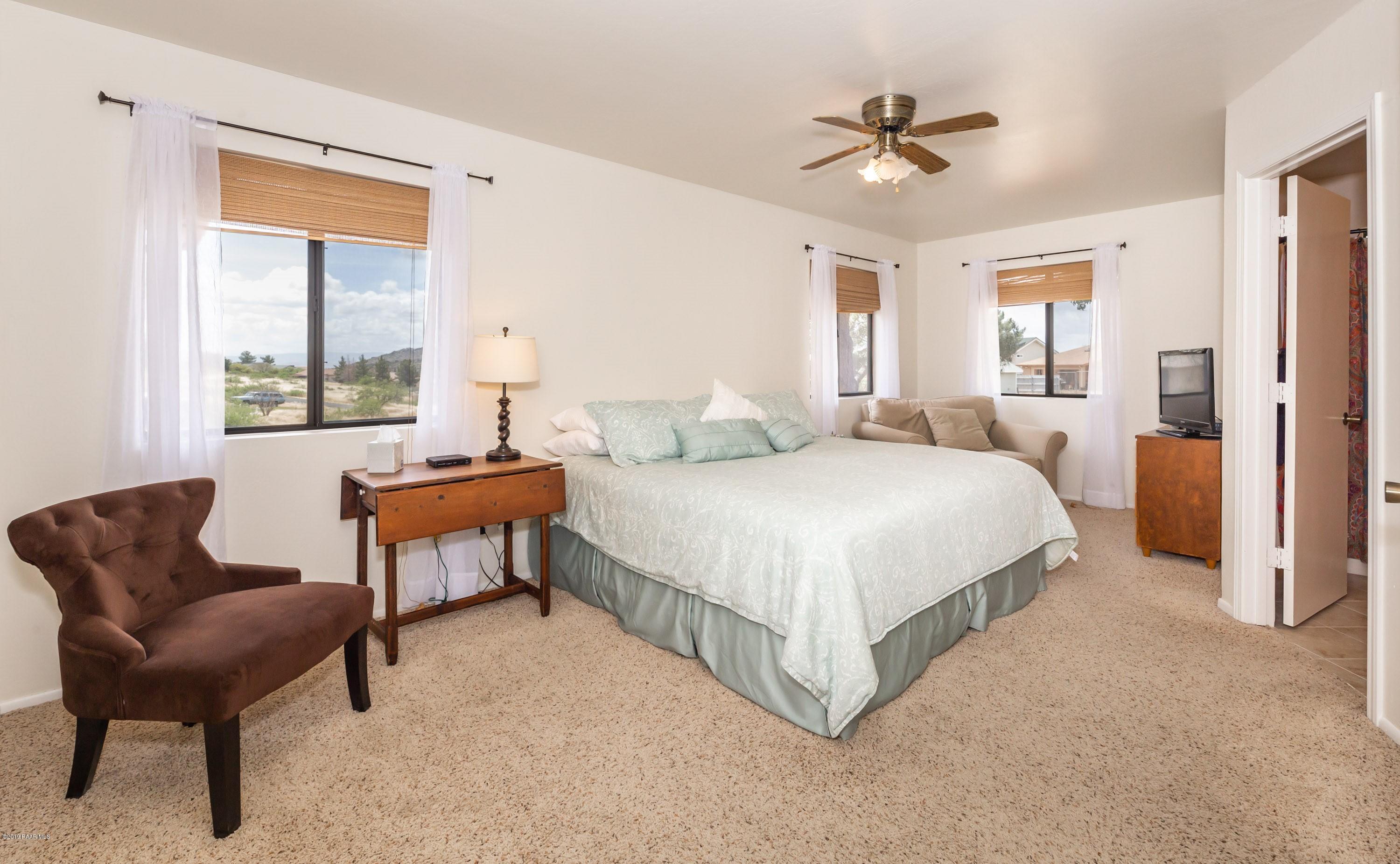 17571 East Hummingbird Lane Mayer, AZ 86333 - Photo 8 of 16 a spacious bedroom with a bed and a chair