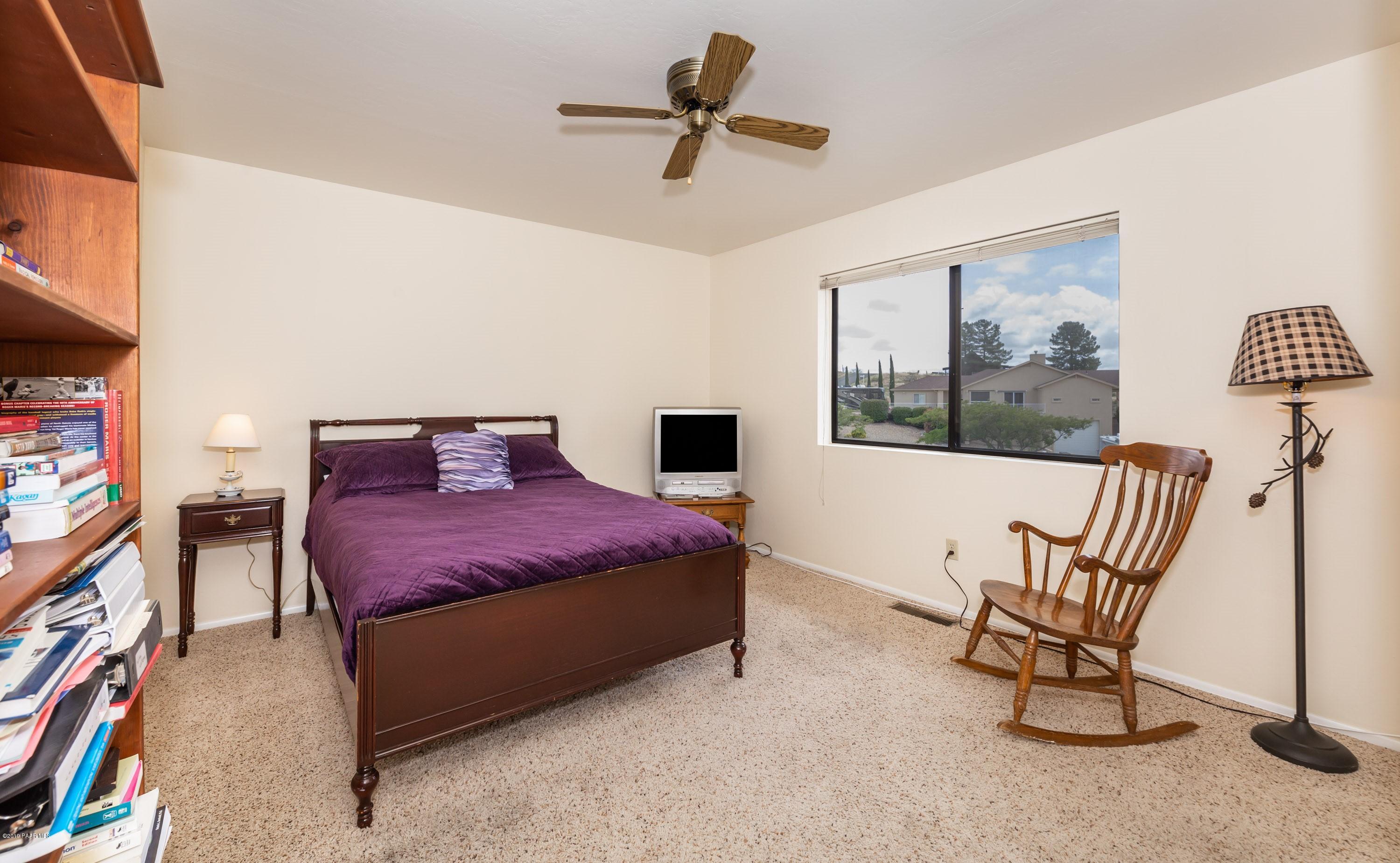 17571 East Hummingbird Lane Mayer, AZ 86333 - Photo 10 of 16 a bedroom with a bed a chair and potted plant on the dresser