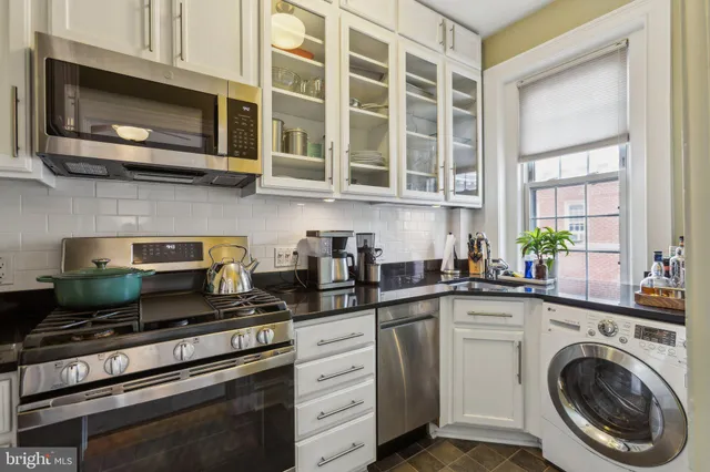 a kitchen with stainless steel appliances granite countertop white cabinets a stove a sink and dishwasher