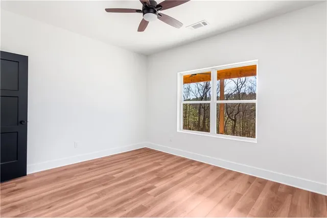 a view of an empty room with a window and wooden floor