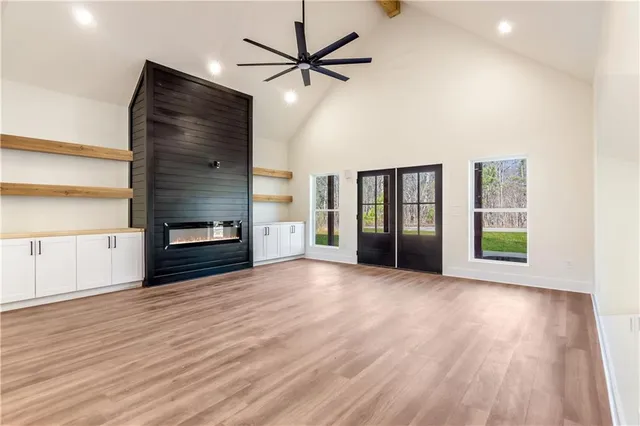 a view of an empty room with window and wooden floor
