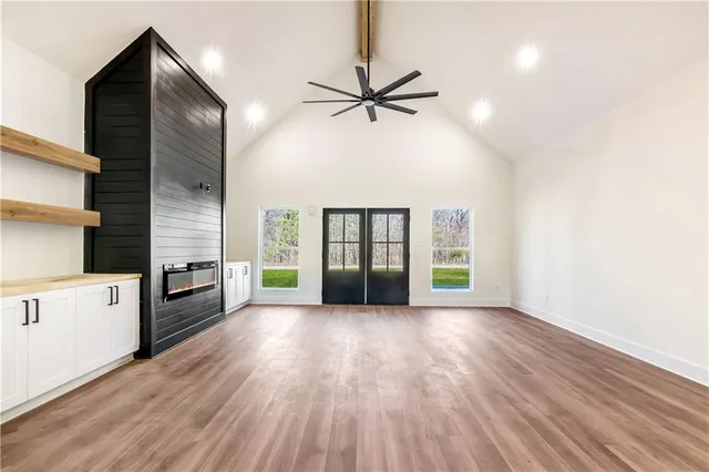 a view of a kitchen with wooden floor a ceiling fan and windows