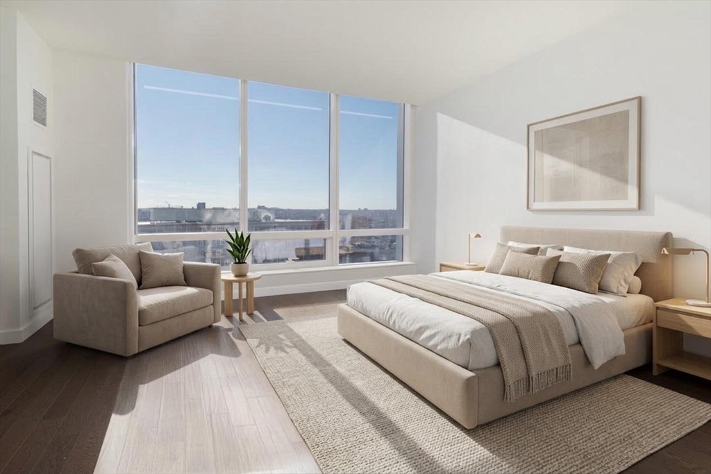 a bedroom with a bed couch and three large window