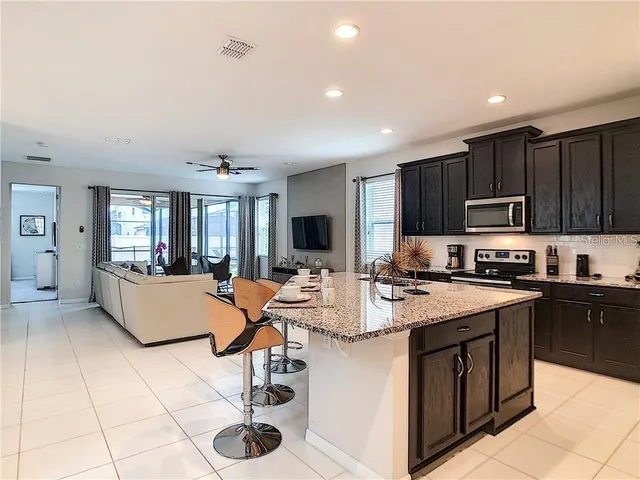 a kitchen with stainless steel appliances granite countertop a stove top oven a sink dishwasher and white cabinets with wooden floor