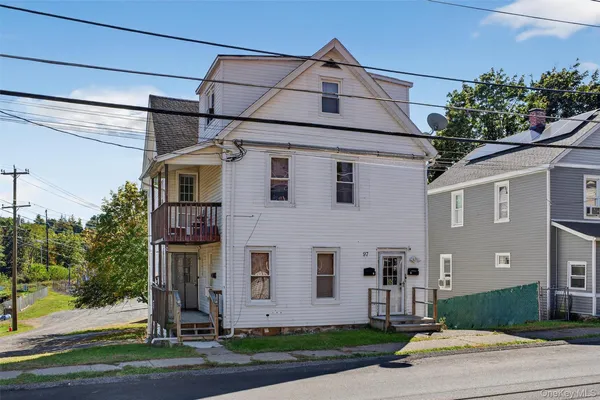 a front view of a house with a yard and potted plants