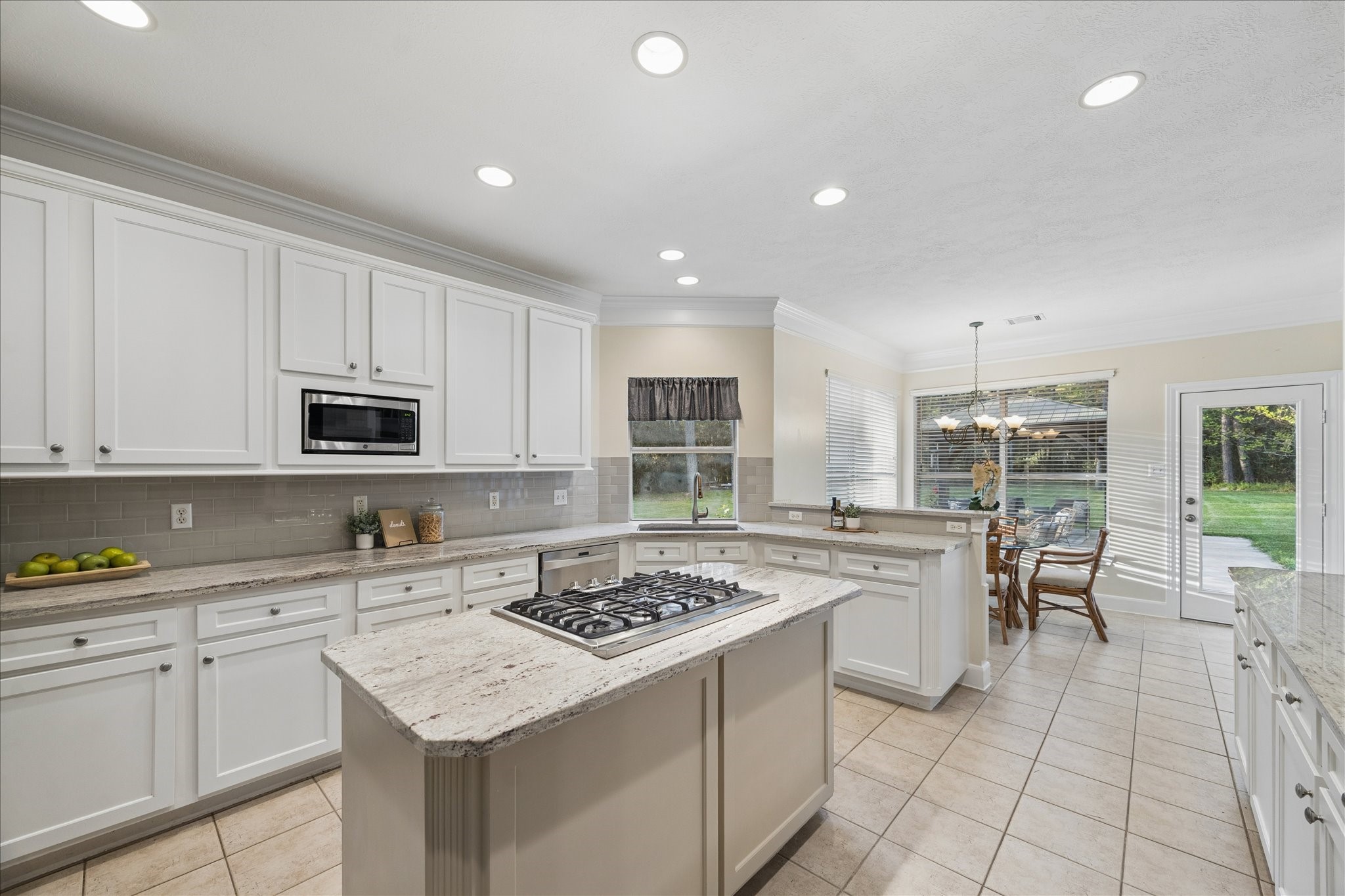 14530 Millhouse Road Pinehurst, TX 77362 - Photo 13 of 46 Light and bright kitchen with island and gas cooktop, granite countertops, tile backsplash, recessed lighting, and extensive cabinetry, with adjacent breakfast area and access to the backyard.