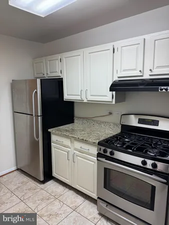 a kitchen with granite countertop white cabinets and stainless steel appliances