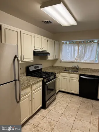a kitchen with granite countertop a stove sink and cabinets