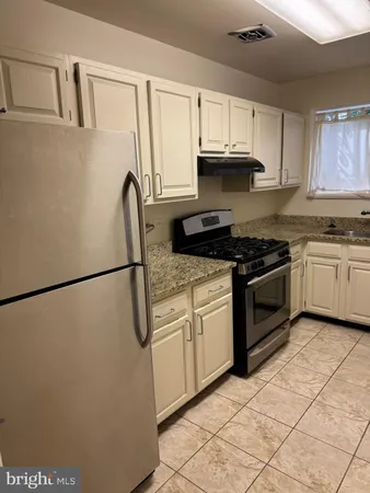 a kitchen with granite countertop a refrigerator stove top oven and sink