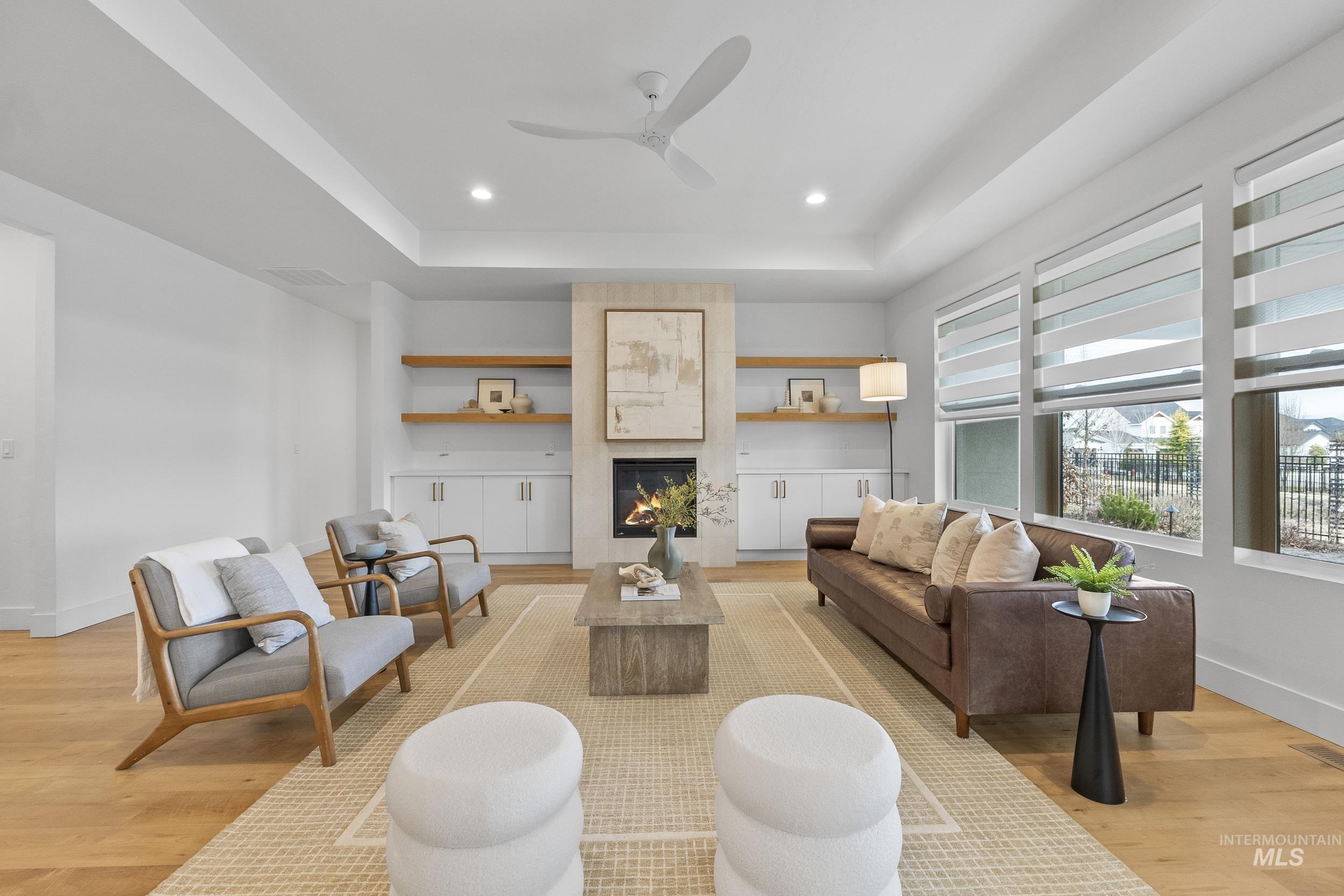 4320 South Selatir Way Meridian, ID 83642 - Photo 11 of 44 Living area featuring a tray ceiling, light wood-style flooring, a tile fireplace, ceiling fan, and recessed lighting