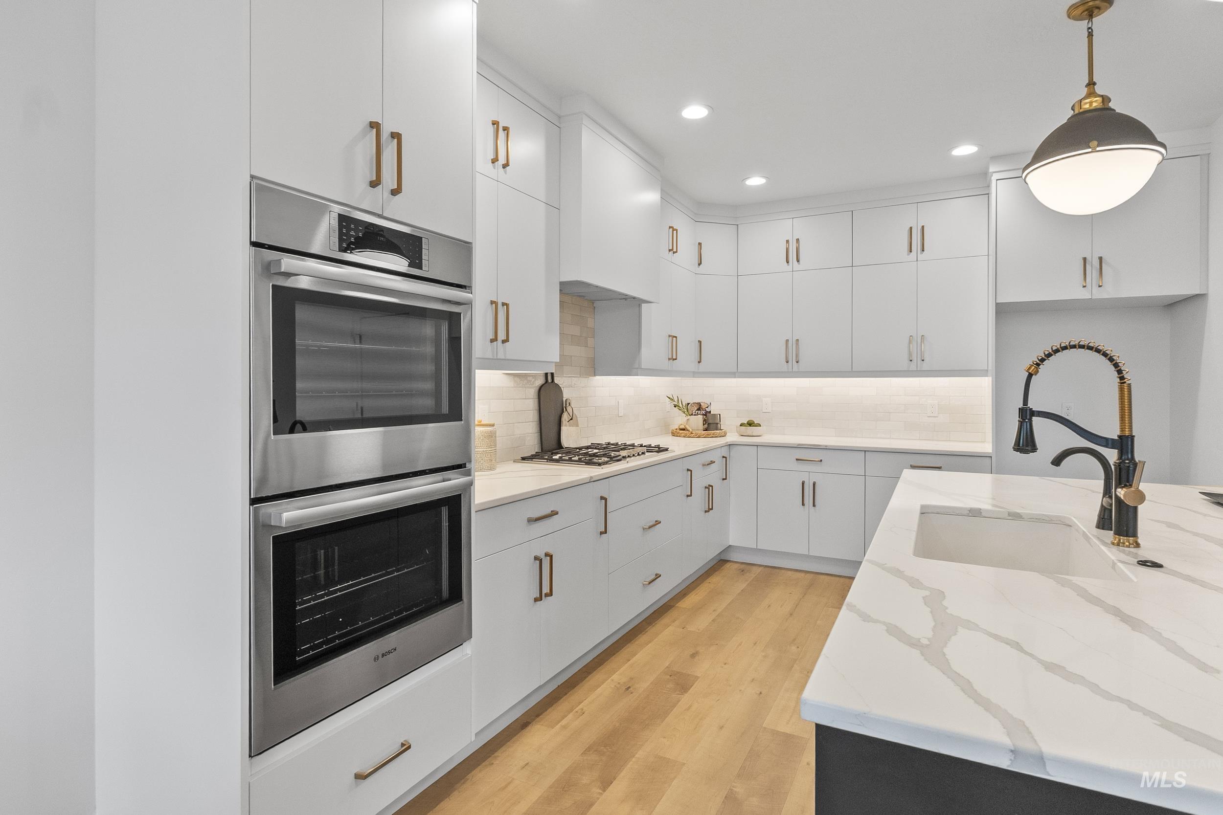4320 South Selatir Way Meridian, ID 83642 - Photo 15 of 44 Kitchen featuring stainless steel appliances, decorative light fixtures, backsplash, light wood finished floors, and light stone countertops