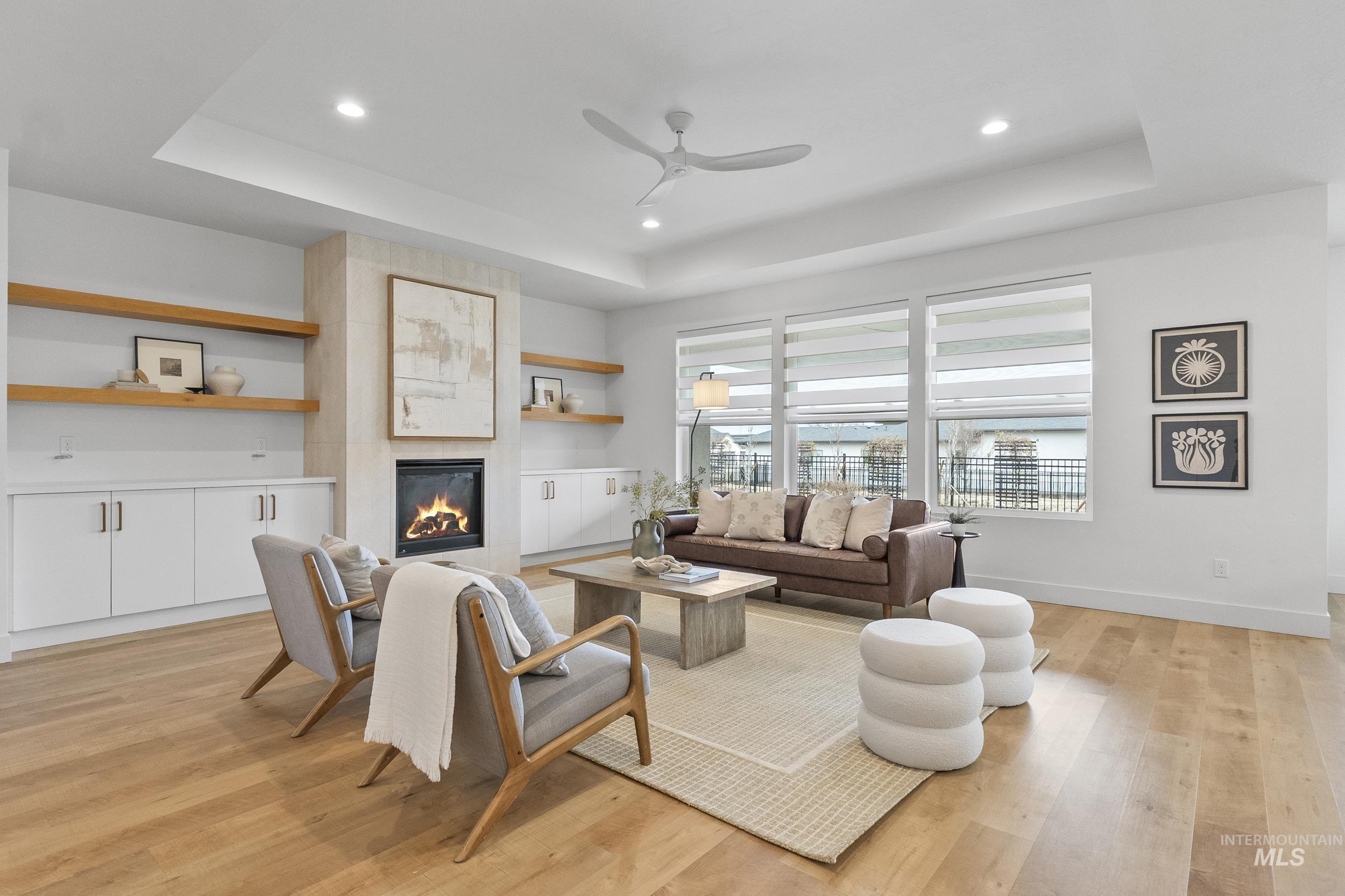 4320 South Selatir Way Meridian, ID 83642 - Photo 8 of 44 Living room with ceiling fan, light wood finished floors, recessed lighting, a tiled fireplace, and a tray ceiling