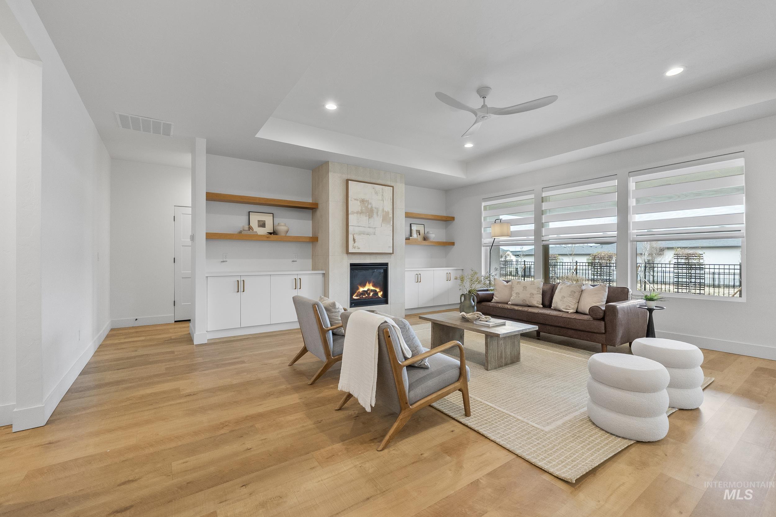 4320 South Selatir Way Meridian, ID 83642 - Photo 9 of 44 Living area with a fireplace, recessed lighting, light wood-style flooring, ceiling fan, and a raised ceiling