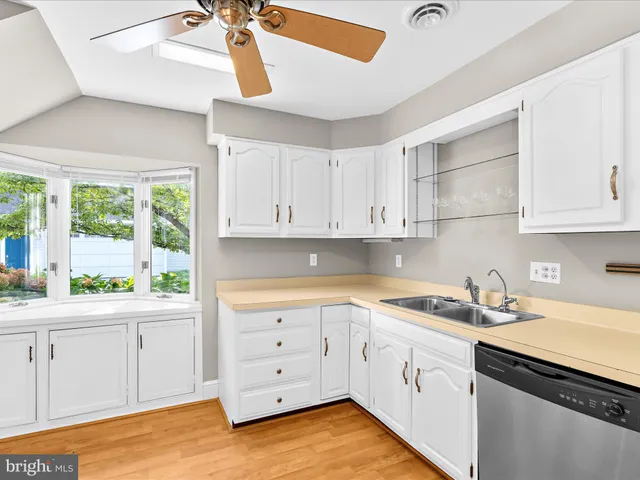 a kitchen with white cabinets and window