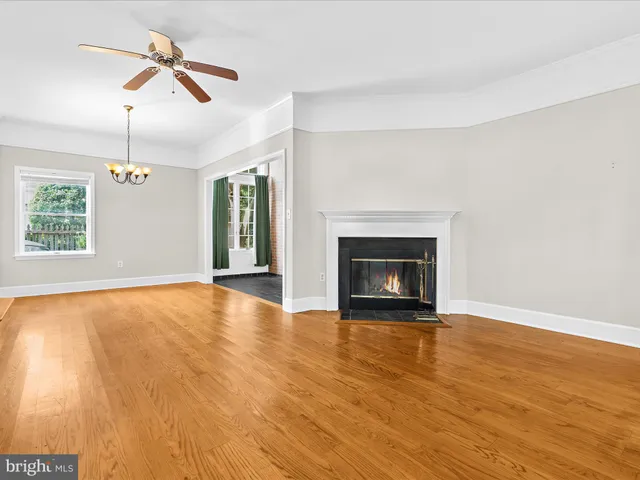 an empty room with wooden floor ceiling fan and windows